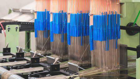 A machine is weaving a piece of fabric. The machine is made up of many parts, including a large...