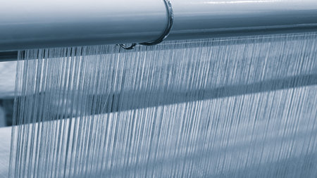 A machine is weaving a piece of fabric. The machine is made up of many parts, including a large...