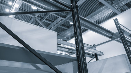A warehouse with lots of metal racks and white cardboard boxes. The beams are of different shapes and sizes, and lights shine from the metal ceiling.の写真素材