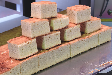 A stack of white square cakes on a table. The cakes are cut into small squares and arranged in a...