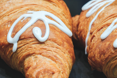 Two croissants with white icing on top. The icing is spread out and not too thickの写真素材