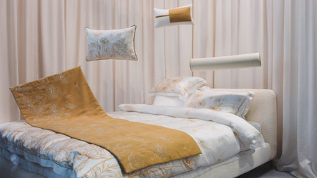 A bed with a yellow blanket and white pillows. The bed is surrounded by curtains and a white...