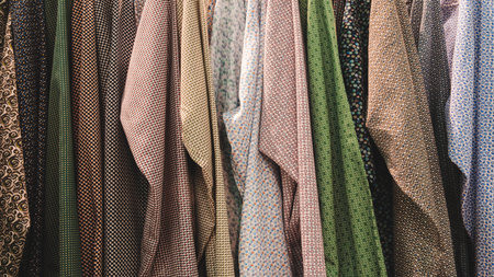 A row of clothes with different patterns and colors. The clothes are hanging on a rackの写真素材