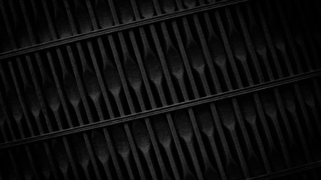A black and white photo of a metal railing with a black background. The railing is made of metal and...