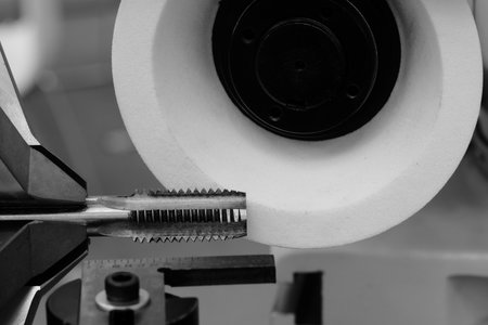 Machine with abrasive white disk used for sharpening milling cutter tool, industrial concept backgroundの写真素材