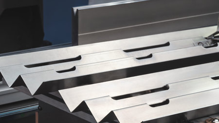 Series of metal pieces are being cut by a machine. pieces are all the same size and shape, and they...