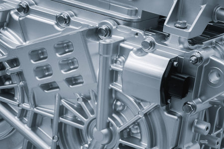 A close up of a car engine with many bolts and screws. The engine is silver and it is a part of a...