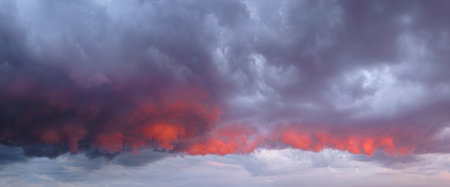 Beautiful dramatic crimson red sunset with cloudy sky. The sky is covered with clouds and the sun is...