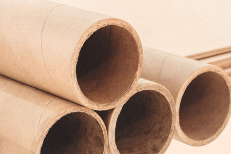 A stack of cardboard tubes, tubes are brown and are arranged in row as background template pages and banners delivery logistics conceptの写真素材