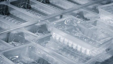Transparent and empty plastic food packaging containers stacked on conveyor of packaging machine,...