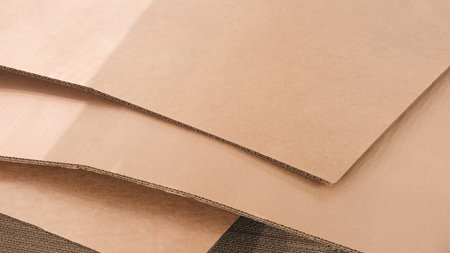 Brown cardboard sheets for packaging is neatly placed in a stack for further use as background for template pages and banners delivery logistics conceptの写真素材