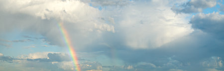 wide panoramas of the sky with a rainbow. The sky is blue with many clouds. The clouds are scattered...