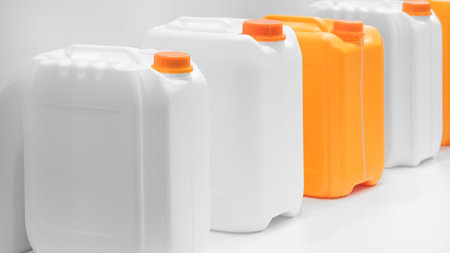 On the table is a row of plastic containers for liquids: some are white, others are orange. All the...