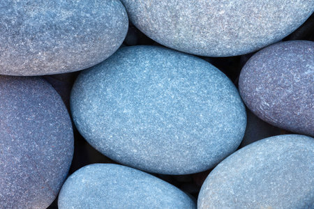Pebbles stones on seashore as texture background for design of web banner template page. many stones and they are different in color and size, dry stones illuminated by sunの写真素材