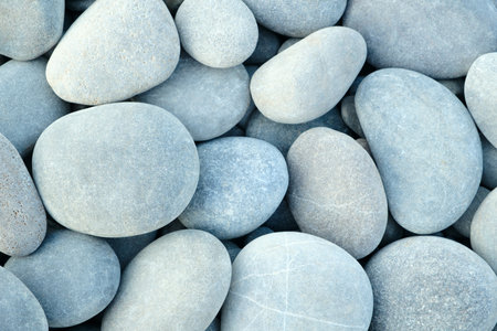 Pebbles stones on seashore as texture background for design of web banner template page. many stones and they are different in color and size, dry stones illuminated by sunの写真素材