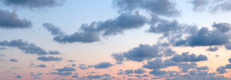 The sky is filled with clouds and the sun is setting. The clouds are white and the sky is blue