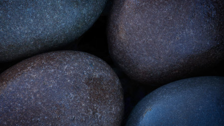 Pebbles round wet smooth colorful stones on sea beach illuminated by morning sun as texture spa...