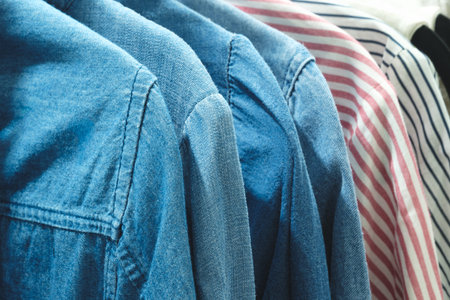 Row of blue and white striped shirts are hanging on a clothesline. The blue shirts are all different...