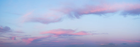 A wide panorama of a beautiful pink and blue sunset sky with clouds. The sky in pink and blue tones...