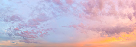 A wide panorama of a beautiful pink-orange sky with clouds. The sky is overcast, the sun is setting.の写真素材