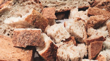 slices of bread on a wooden cutting board. One slice is cut in half. The other slice is wholeの写真素材
