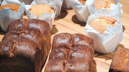 table with a variety of baked goods, including muffins, scones, and cakes. muffins are in paper...
