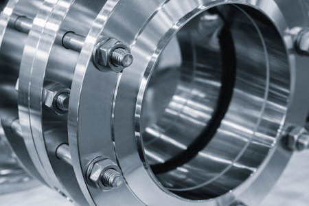 Stainless steel shiny rings connected with long bolts as part of industrial piping system,...