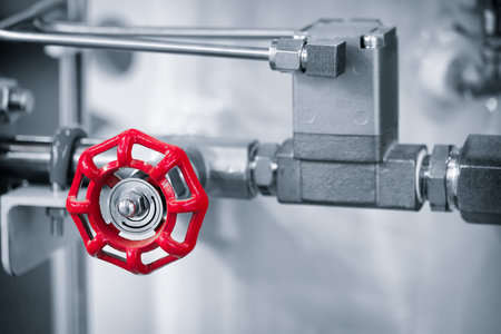 Red valve attached to a pipe which is part of a large industrial machine, industrial concept...
