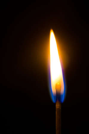 Silhouette of a burning match over black backgroundの写真素材