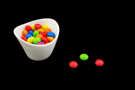 Multicolored candies in a bowl isolated on black backgroundの写真素材