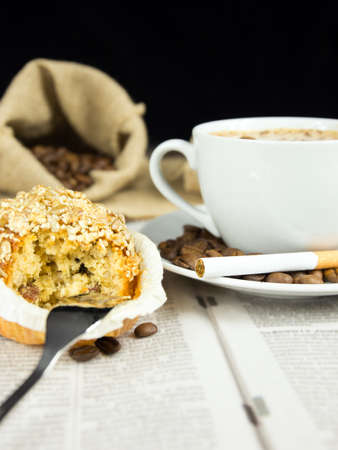 Cup of coffee, muffin and a  cigarette arranged on a newspaperの写真素材