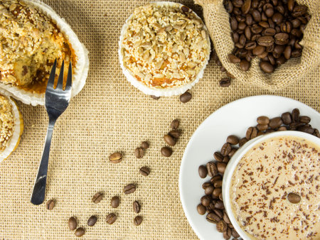 Aerial view of cup of coffee, roasted beans and muffins