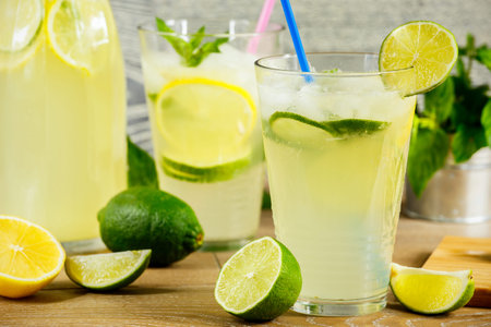 Refreshing lemonade drink and ripe fruits against wooden background