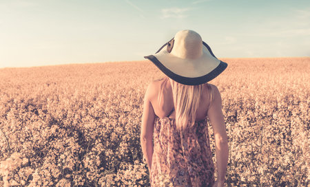 Retro style photo of girl on yellow rape fieldの写真素材
