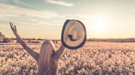 Retro style photo of girl on yellow rape fieldの写真素材