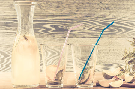 Refreshing lemonade drink and ripe fruits against wooden background