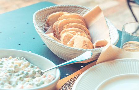 Outdoor breakfast setting with mayonnaise salad and slices of breadの写真素材