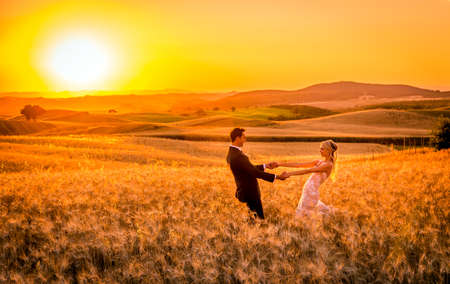 PIENZA, ITALY - JUNE 27, 2015: anonymous newlyweds during photo session on tuscan fields near historic Pienza townのeditorial素材