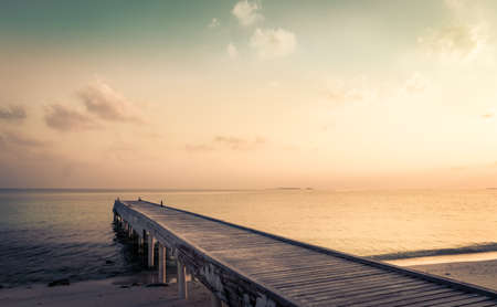 Wooden jetty and amazing sunrise over Indian ocean in Maldivesの写真素材