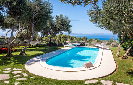 Private swimming pool with turquoise water and beautiful gardenの写真素材