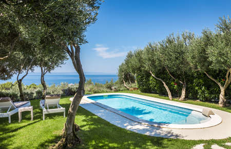 Private swimming pool with turquoise water and beautiful gardenの写真素材