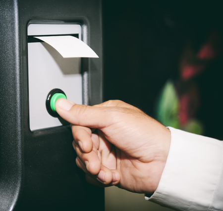 Hand pressing button and getting ticket from a machineの写真素材