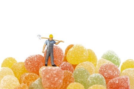 Miniature Worker Working On Gummy Candies With Fruit Juice, Isolated On White Backgroundの写真素材
