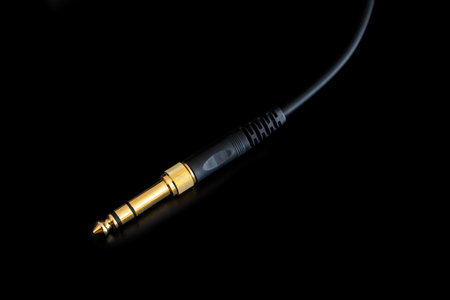 3.5mm female jack converter to 6.5mm male TRS jack or stereo jack with black cable, on a black surfaceの写真素材