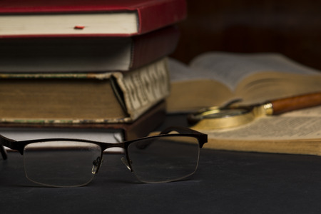 Books with glasses on black table and wooden background. High resolution image depicting reading/bokks industry.の写真素材