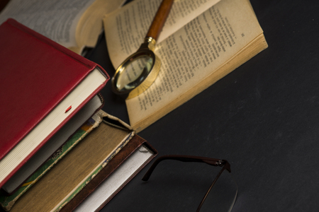 Books with glasses on black table and wooden background. High resolution image depicting reading/bokks industry.の写真素材