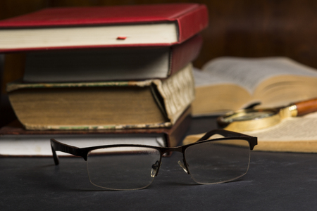 Books with glasses on black table and wooden background. High resolution image depicting reading/bokks industry.の写真素材