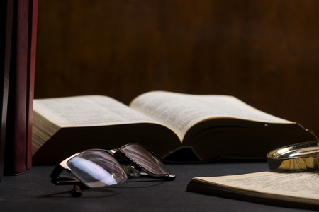Books with glasses on black table and wooden background. High resolution image depicting reading/bokks industry.の写真素材