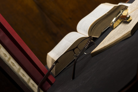 Books with glasses on black table and wooden background. High resolution image depicting reading/bokks industry.の写真素材