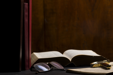 Books with glasses on black table and wooden background. High resolution image depicting reading/bokks industry.の写真素材
